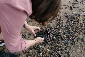 Photo of a Woman by the lake in a Summer Camping Activity. Travel location of popular tourist outdoor. View of beautiful sea shore Landscape. Vacation in a camp