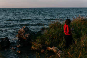 Photo  of a Summer Camping Activity. Travel location of popular tourist outdoor. View of beautiful Sea Landscape and Woman make selfie. Vacation by the lake in a camp with a bonfire and tent