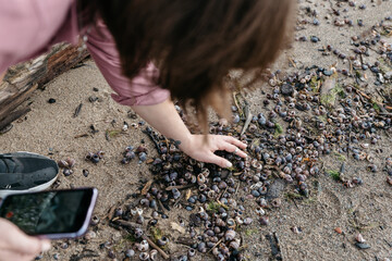 Photo of a Woman by the lake in a Summer Camping Activity. Travel location of popular tourist outdoor. View of beautiful sea shore Landscape. Vacation in a camp