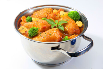 Frango ao molho na caçarola com brócolis, batatas, cenouras e champignons em fundo branco para recorte.