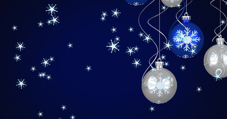 Image of blue and silver christmas baubles decoration and snowflakes falling on blue background