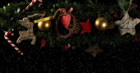 Image of baubles decorations on christmas tree with snow falling