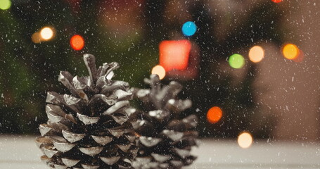 Image of christmas pine cones, lights and decorations with snow falling