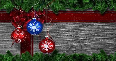 Image of christmas decorations, baubles and ribbon with snow falling