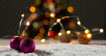Image of christmas decorations, baubles and lights with snow falling