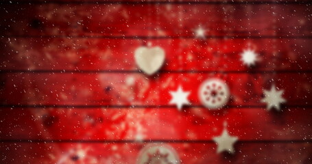 Image of christmas baubles decoration with snow falling on red boards