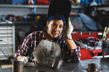 Mixed race female car mechanic welding car part in workshop