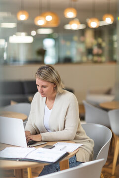 Thoughtful caucasian female business creative using laptop at workplace cafeteria