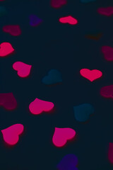 Romantic vertical background for the decoration of the holiday of all lovers. Minimalistic dark black background with hearts