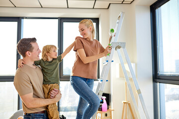 Family time: parents shows son repair tools, using roller for painting. Side view portrait of...