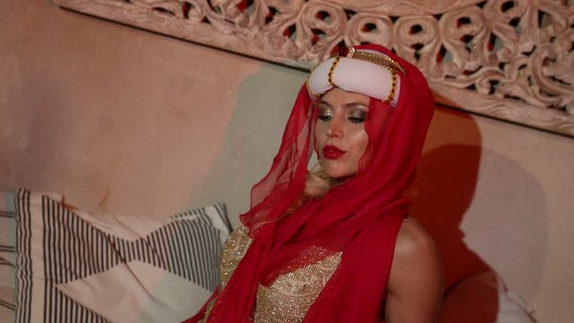portrait of a woman in a turban, a red scarf and a sequined dress in the sunset light. the camera is moving
