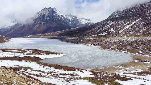 frozen sela lake through buddhist flags with snow cap mountains and bright blue sky at morning