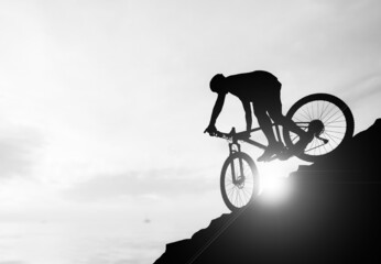 Fototapeta na wymiar A silhouette of a cyclist descending from the mountain