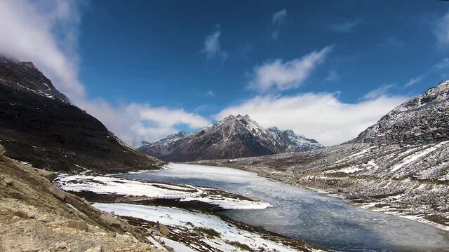 time lapse of snow cap mountains with frozen lake and bright blue sky at morning from flat angle