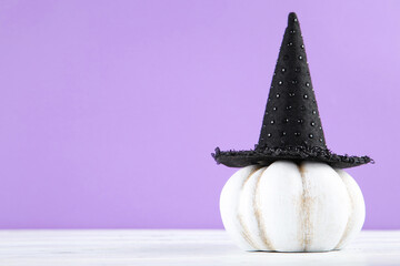 Halloween pumpkin with black hat on purple background