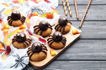Halloween cookies with chocolate spiders and candies on wooden background