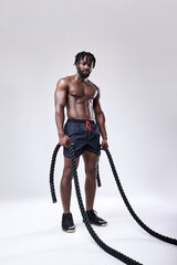 slim well-built afro american athlete preparing for training with battle ropes, full-length portrait, isolated white background, studio shot. bodybuilding, cross fit, weightlifting, sport, fitness