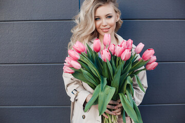 Beautiful blond woman with flowers tulips outdoors