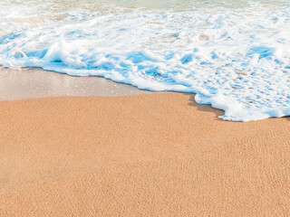 Fototapeta na wymiar wave on a sandy beach on a sunny day, copy space