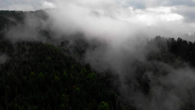 Amazing Aerial View. Flying over the high mountains in beautiful fog . Aerial camera shot. Air clouds. Fog. Steam.