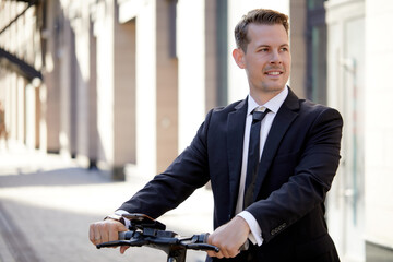 Eco vehicle. elegant, stylish business man riding electrical scooter on city street in daytime, leisure time, having rest, taking a break. caucasian guy enjoy riding modern vehicle. people lifestyle