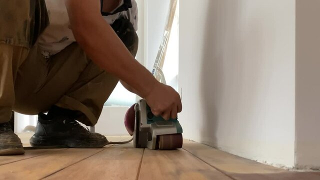 Carpenter performs repair work on grinding parquet floors..Sanding a wooden floor with a grinder.