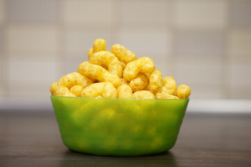 Green plate of Puffcorn on the table - obrazy, fototapety, plakaty