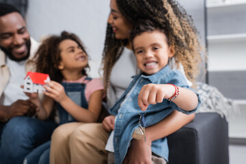 selective focus of key in hand of african american boy sitting near blurred family