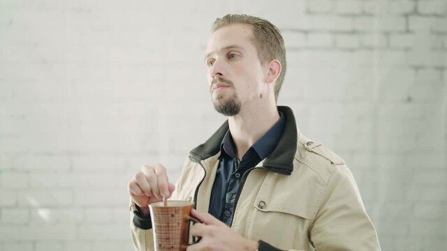 Man with coffee mug mixing and not impressed listening 4K