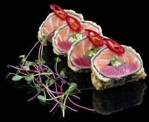 Large sushi roll with salmon, tuna and caviar on glossy black background