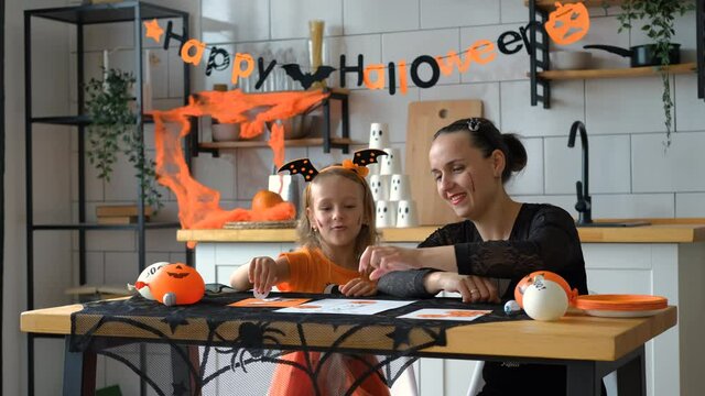 Little Girl with Mother Playing Halloween Tic-Tac-Toe Baord Game in the Kitchen. People and Halloween Holiday Celebration Concept