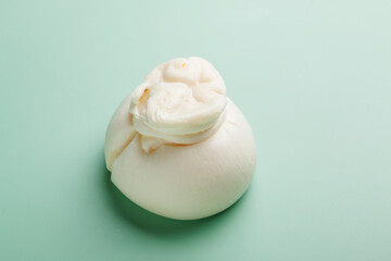 Delicious fresh cheese made from cream and milk - burrata. Italian tender cheese on mint background