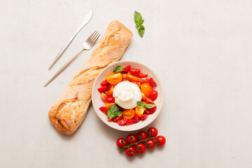 Delicious fresh cheese made from cream and milk - burrata. Italian tender cheese with fork and knife. Bread and salad of tomatoes and herbs, cherry tomatoes on a twig.