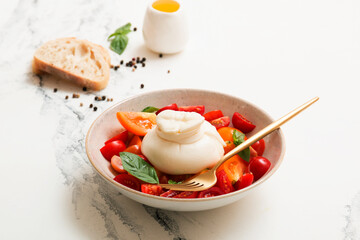 Delicious fresh cheese made from cream and milk - burrata. Italian delicate cheese with olive oil. Bread and salad of tomatoes and herbs, cherry tomatoes on a twig.