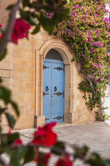 Mdina, Malta: traditional Maltese house with colorful doors, purple bougainvillea flowers on the limestone wall.