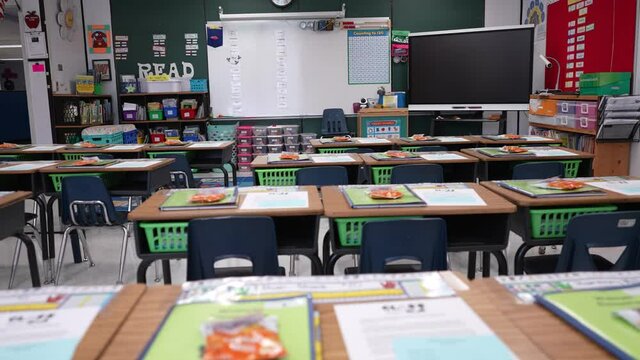 Slow push in over school desks to blackboard or white board and interactive whiteboard in empty classroom during pandemic.