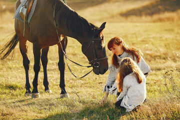 Mother and daughter in a field playing with a horse - obrazy, fototapety, plakaty