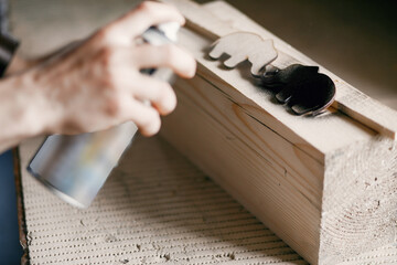 Man holding paint spray and painting wood