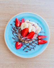 Sponge cake with strawberries, banana and liquid chocolate on top