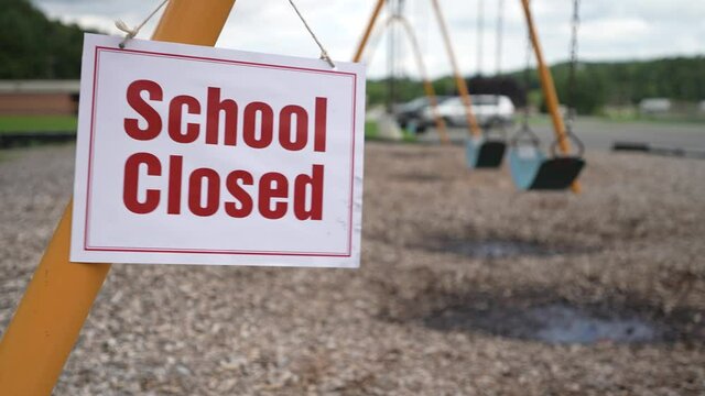School Closed sign sways in the wind at a school playground.