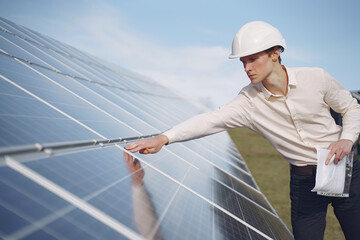 Businessman in a white helmet near solar battery