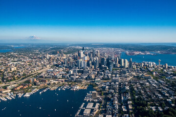 The Seattle skyline and surrounding areas as seen from the air on a clear blue sky day, with Mt. Rainier in the background