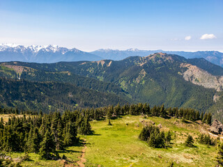 Obraz premium Hiking trails through mountains with forests and snow capped peaks