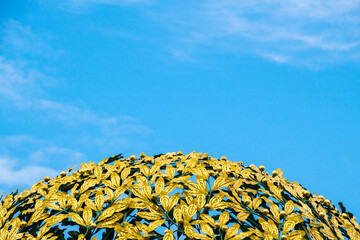 ein Dach aus gelben Blättern aus Metall im blauen Himmel