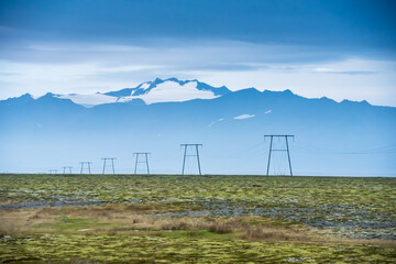 Strommasten in der Reihe vor schneebedeckten Bergen