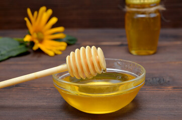 honey dipper and honey in a glass bowl close-up