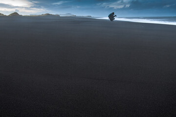 schwarzer Strand mit Person am Horizont