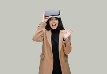 Beautiful woman in fashionable clothes over gray background. Girl in glasses of virtual reality expresses happiness. Augmented reality, game, future technology concept. VR.