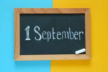 Flat lay. Yellow-blue background. September 1. Back to school. In the center is a chalk board. 