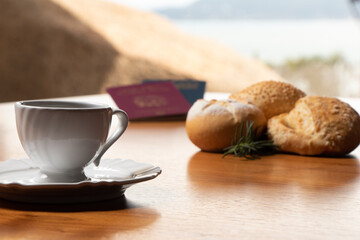 In the foreground, Italian and Brazilian passport, in the background and blurred a small cup of coffee and three loaves of bread with a sprig of rosemary decorating the scene.